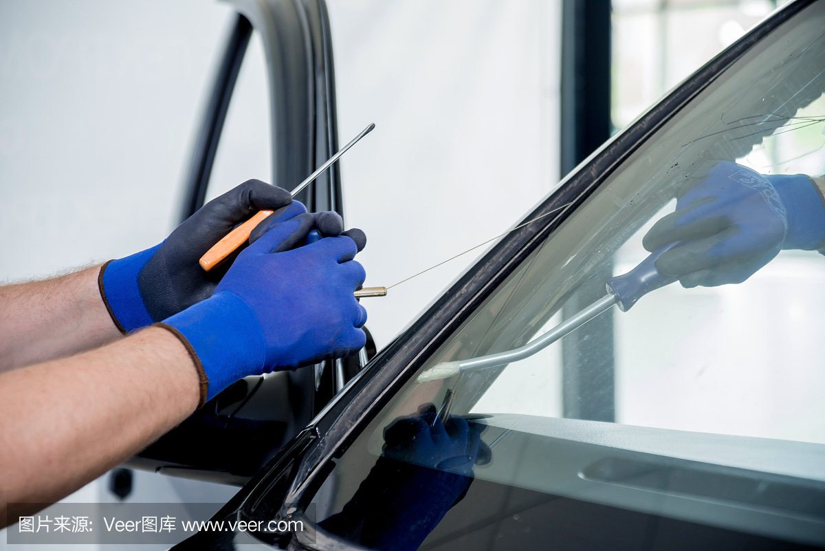 汽车专用工人在汽车维修站车库拆除旧挡风玻璃或汽车的挡风玻璃。
